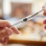 Eine Hand zieht einen CBD Preroll aus seinem transparenten Behälter.