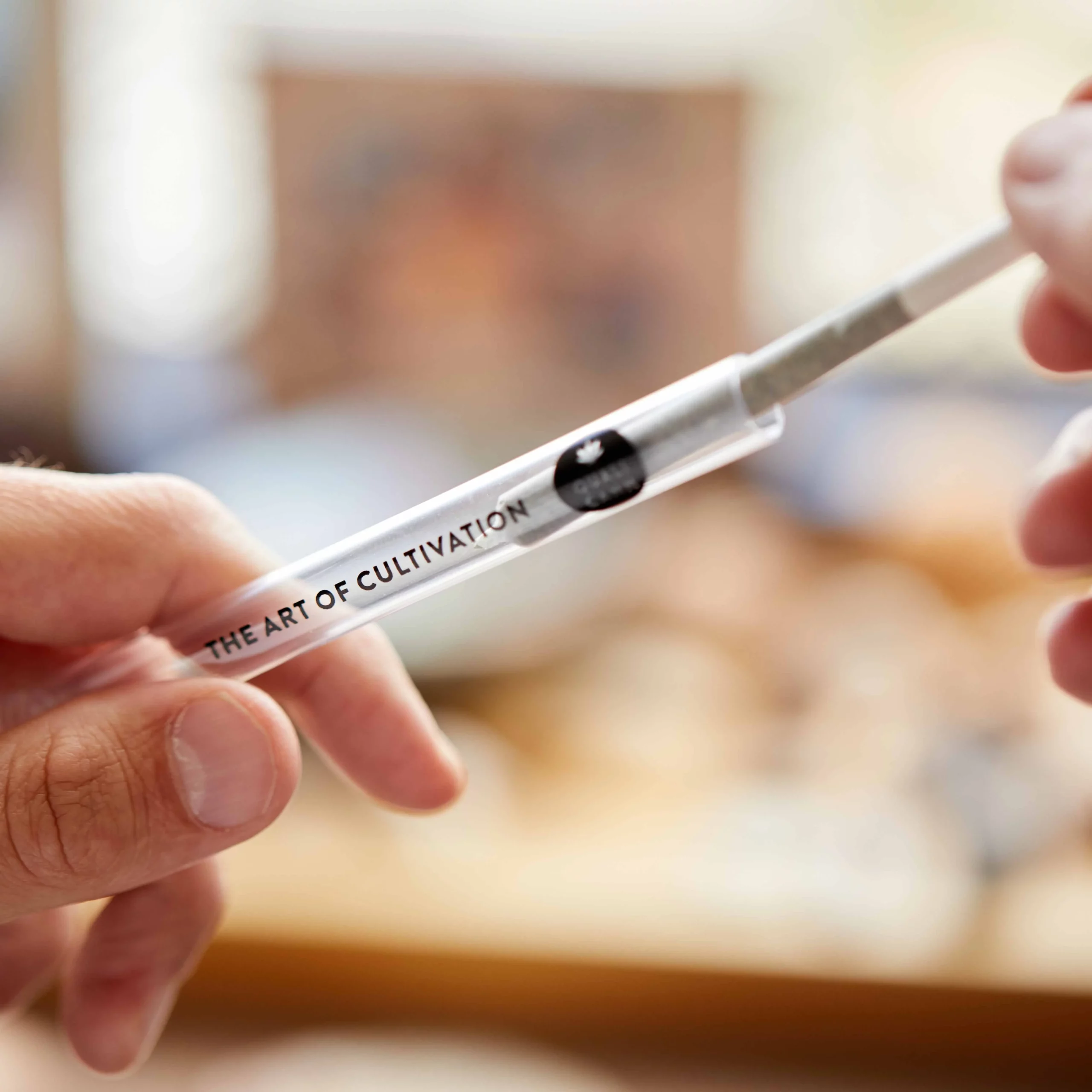 Eine Hand zieht einen CBD Preroll aus seinem transparenten Behälter.