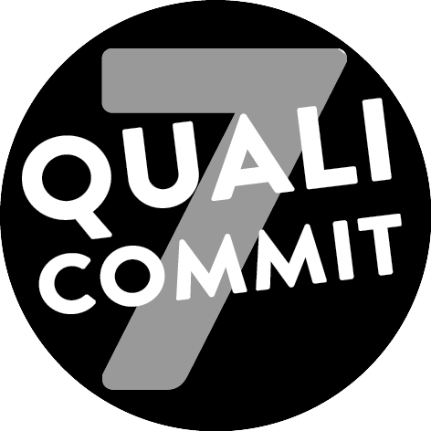 Ein schwarzer Button mit einer grauen '7' und dem Schriftzug 'Quali Commit'. Unsere Verpflichtung zu Qualität und Engagement in einem eleganten Design.