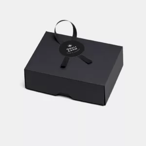 Diese schwarze Schachtel, versiegelt mit dem Qualicann-Kleber, birgt Weihnachtsfreuden in höchster Qualität. Gönn dir den Luxus, die festliche Schleife zu lösen und die Magie zu entfesseln.