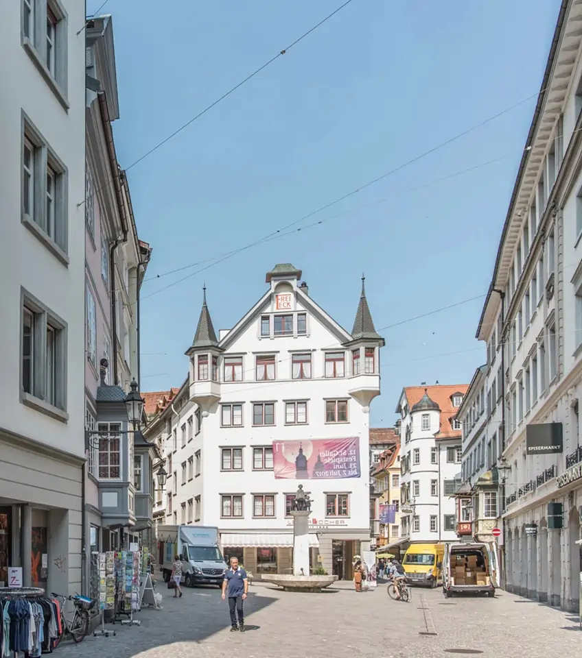 Altstadt von St. Gallen mit historischen Gebäuden, Brunnen und belebter Fussgängerzone unter blauem Himmel – typische Stadtszene aus der Ostschweiz.