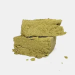 Zwei helle bröselige CBD Pollen Stücke in Blockform auf hellem Hintergrund