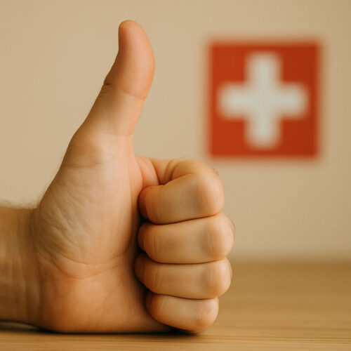 Daumen hoch vor unscharfer Schweizer Flagge – symbolisches Bild für Zustimmung oder gesetzliche Freigabe in der Schweiz.